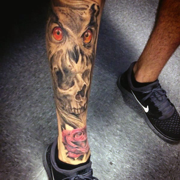 Tattooed leg featuring a skull with red eyes and a rose near the ankle
