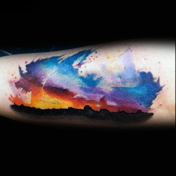 Colorful, abstract wolf tattoo with a vibrant sky effect on an arm