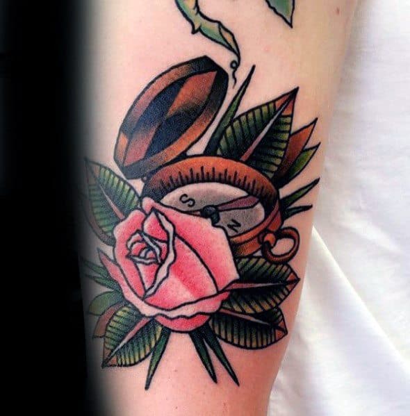 Traditional-style compass tattoo with bold outlines, vibrant colors, and a pink rose, symbolizing love, direction, and adventure.