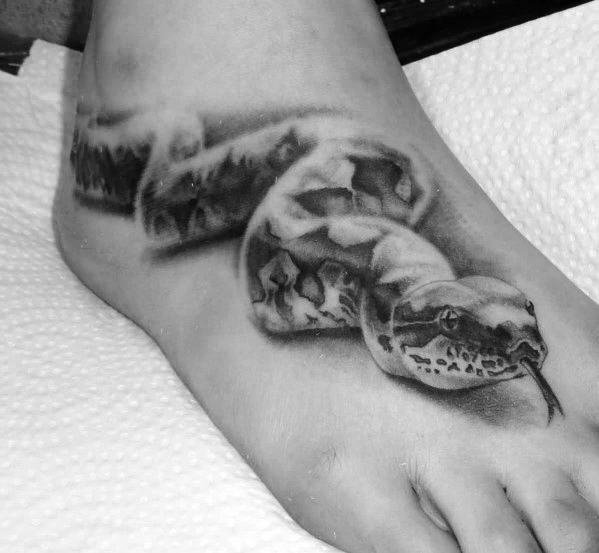 Black and gray snake tattoo wrapped around a foot, with detailed scales and tongue visible