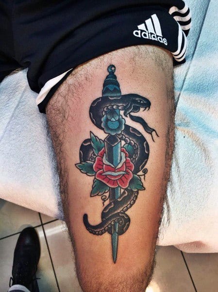 Traditional snake and dagger tattoo on thigh, featuring bold black, red, and blue ink with a rose and classic old-school shading.