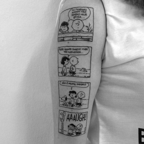 Black and white tattoo of a four-panel Peanuts comic strip featuring Charlie Brown, Lucy, and Snoopy, placed on a person's arm.