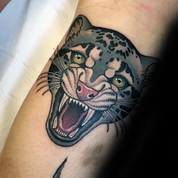 Neo-traditional snow leopard tattoo with a wide-open mouth, sharp teeth, and bold black lines, accented by striking green eyes.