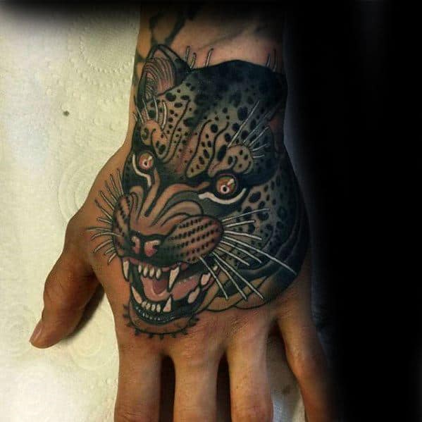 Fierce snow leopard tattoo on the hand in neo-traditional style, featuring bold outlines, sharp teeth, and intense amber eyes.