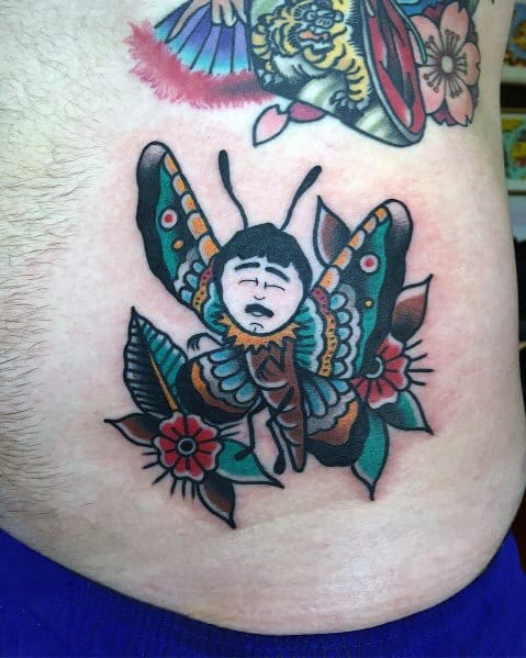 Neo-traditional tattoo of Randy Marsh as a butterfly, featuring bold outlines, vibrant colors, floral details, and a humorous expression.