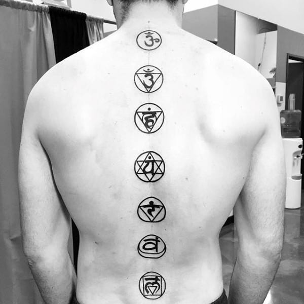 Back view of a person with chakra symbols tattooed vertically along the spine
