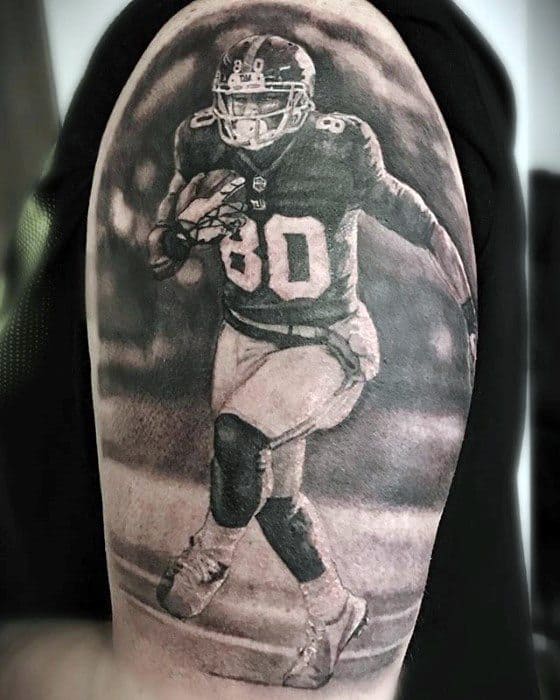 Hyper-realistic black and grey tattoo of a football player in motion wearing jersey number 80, holding the ball mid-play.