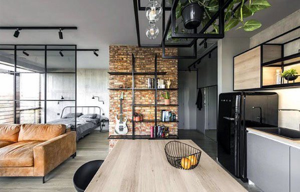 Modern studio with brick accent wall, glass partitions, open shelving, and industrial decor.