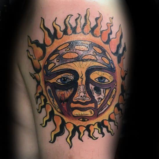 Detailed Sublime sun face tattoo with intense yellow, orange, and black tones, expressive eyes, and radiant flame-like rays.