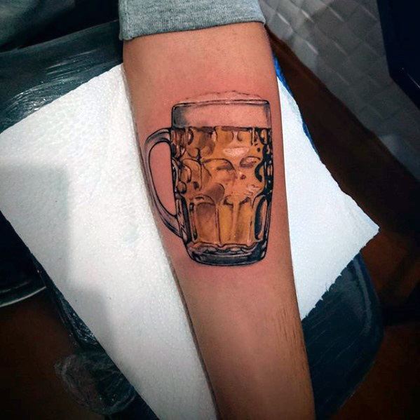Realistic forearm tattoo of a full beer mug with detailed glass reflections and golden hues, capturing the look of a freshly poured pint.