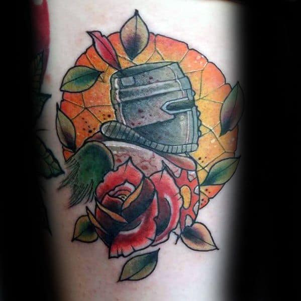 Dark Souls tattoo with a knight helmet, red rose, green leaves, and a glowing orange stained-glass-style background.
