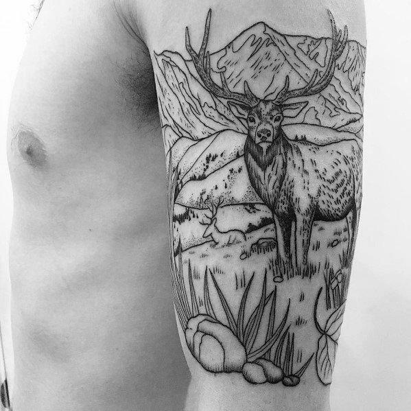 Black and grey elk tattoo on the upper arm, featuring fine linework, a detailed mountain landscape, and natural elements for a scenic design.
