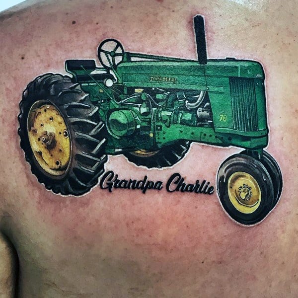 Color tattoo of a classic green John Deere tractor with yellow wheels and the text Grandpa Charlie below as a tribute.