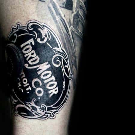 Vintage Ford Motor Co. tattoo on forearm, featuring bold black and white detailing with ornate borders and classic lettering for a nostalgic look.