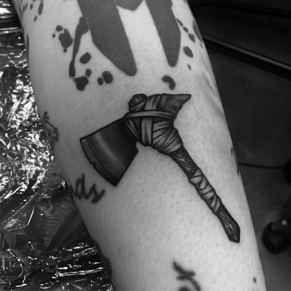 Black and grey hatchet tattoo with a wrapped handle and a sharp, shaded blade, designed with fine details for a rugged and realistic look.