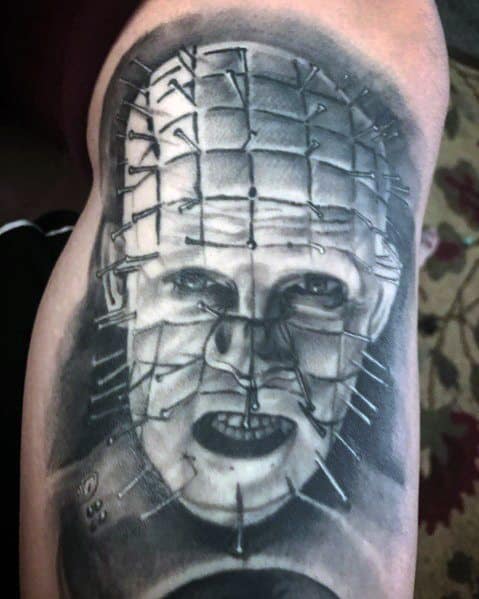 Black and grey *Hellraiser* tattoo of Pinhead with realistic shading, intricate pin details, and a haunting expression for a bold horror design.