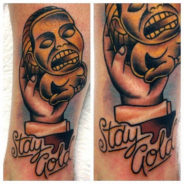 Colorful tattoo of the Golden Idol from *Indiana Jones: Raiders of the Lost Ark*, held in a hand, with the phrase "Stay Gold."