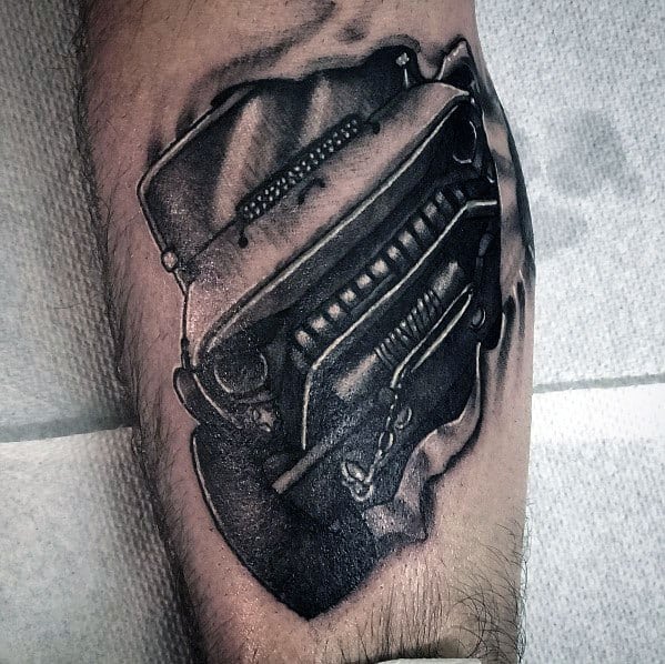 Realistic black and grey tattoo of a Jeep grille with a ripped skin effect, creating a 3D illusion as if the Jeep is emerging from beneath the skin.