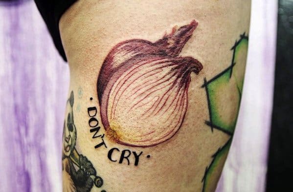 Realistic onion tattoo on the thigh with detailed shading, accompanied by the phrase "DON'T CRY," blending humor with a bold design.