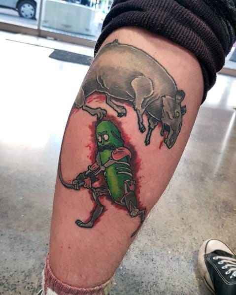 Pickle Rick cyborg tattoo in an action scene, battling a rat with a rope, featuring bold shading and a dynamic design on the calf.