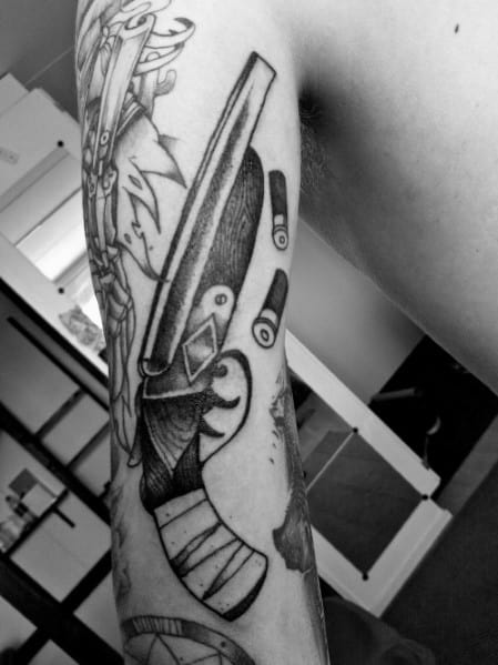 Black and grey tattoo of a double-barrel shotgun with spent shells, featuring bold linework and intricate shading for a rugged and dynamic design.