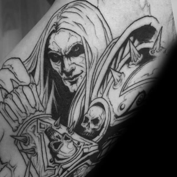 Black and grey tattoo of Kel'Thuzad from World of Warcraft, featuring intricate shading, skeletal armor, and a menacing expression, inked on the arm.