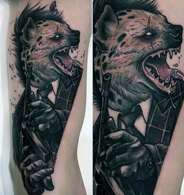 Dark neo-noir style tattoo of a snarling hyena in a suit holding a gun, blending anthropomorphic elements with gritty black and grey shading.
