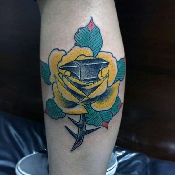 Creative traditional tattoo of an anvil emerging from a blooming yellow rose, with bold green leaves and red accents for a striking visual blend.