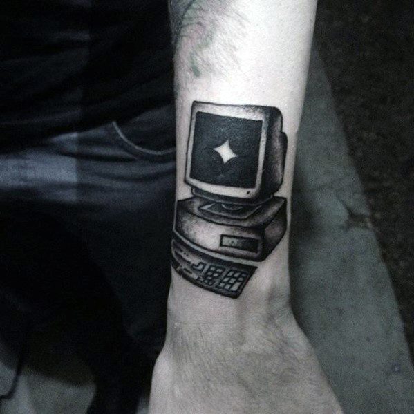 Black and grey tattoo of a vintage computer with a glowing star on the screen, placed on the inner forearm in bold traditional style.