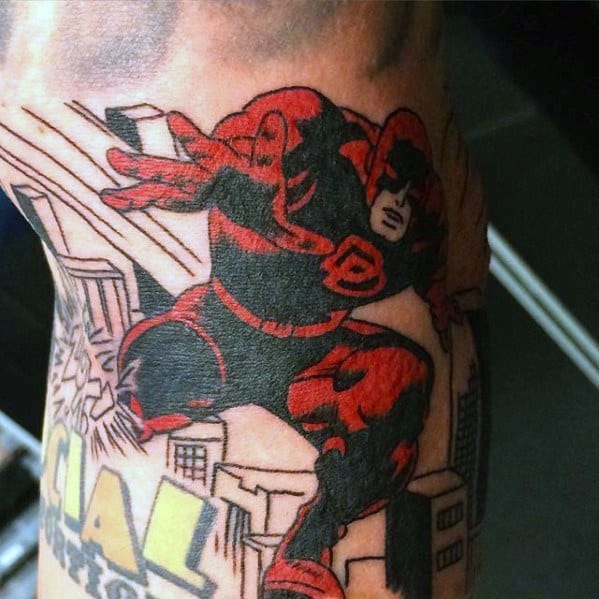 Classic comic-style Daredevil tattoo in red and black, mid-leap over buildings with bold lines and vintage lettering below.
