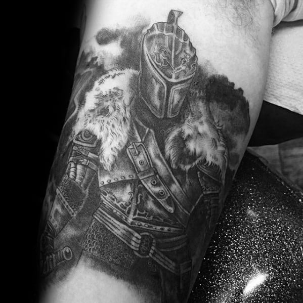 Detailed black and grey tattoo of a Dark Souls knight in fur-lined armor with dramatic shading and a stormy sky background.