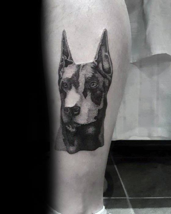 Black and grey Doberman tattoo with a minimalist realistic style, featuring high contrast and a focused, intense expression.