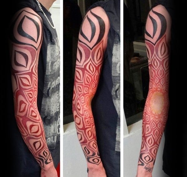 Full sleeve tattoo with bold black tribal shapes and intricate red geometric patterns that form a gradient effect toward a glowing sunburst near the wrist.