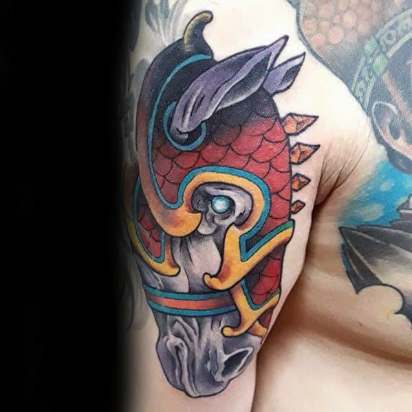 Colorful tattoo of a horse head in ornate armor with red scales, teal and gold accents, placed on the upper arm near the shoulder