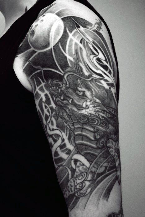 Black and grey Kirin upper arm tattoo with bold contrast, swirling patterns, and intense shading, blending mythic and abstract elements.