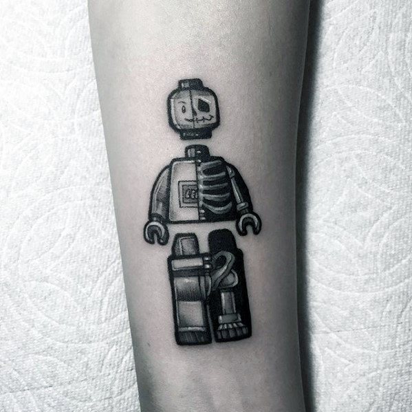Black and grey tattoo of a Lego skeleton minifigure with half-exposed ribcage and skull, featuring bold shading and anatomical detail.