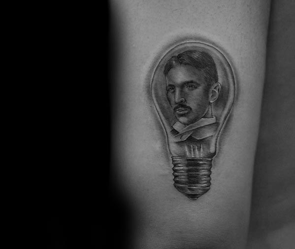 Black and grey tattoo of Nikola Tesla’s portrait inside a realistic lightbulb, symbolizing brilliance and innovation.