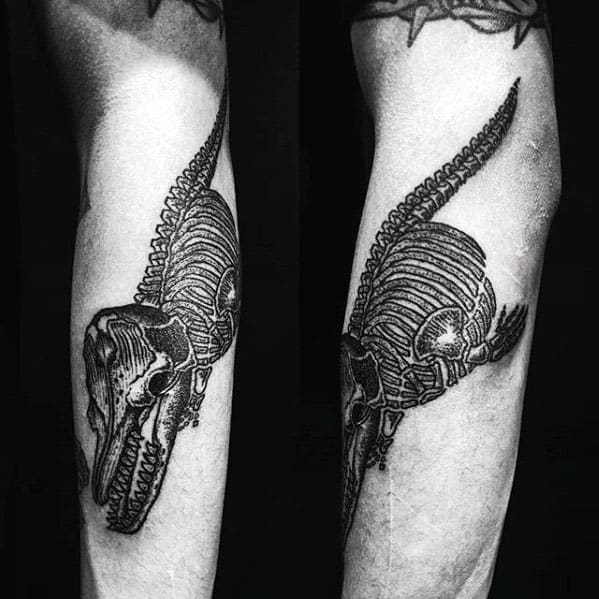Intricate black and gray tattoo on the forearm, showcasing the skeletal structure of an orca whale, with fine detailing to emphasize the bones and texture.