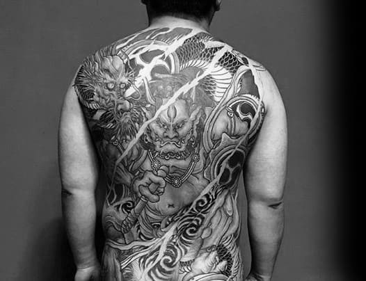 Black and grey Raijin full back tattoo featuring fierce thunder god, lightning bolts, swirling clouds, and intricate traditional details.