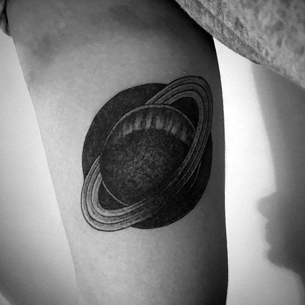 Bold black Saturn tattoo design for men with heavy shading, clean ring lines, and a dark circular backdrop for a minimalist cosmic look.