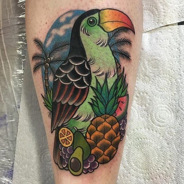 Bright toucan tattoo with tropical fruits, palm trees, and a moonlit sky, creating a vibrant paradise scene on the calf.