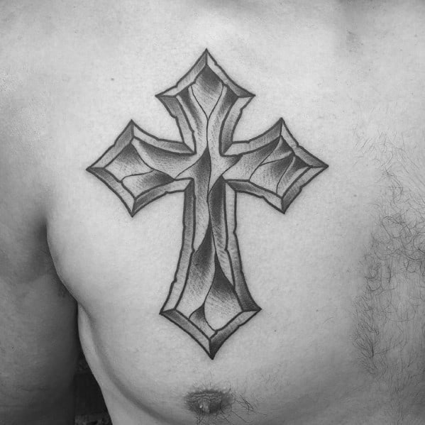 Large chest tattoo of a stylized 3D cross with sharp, beveled edges and detailed shading for a carved stone effect.