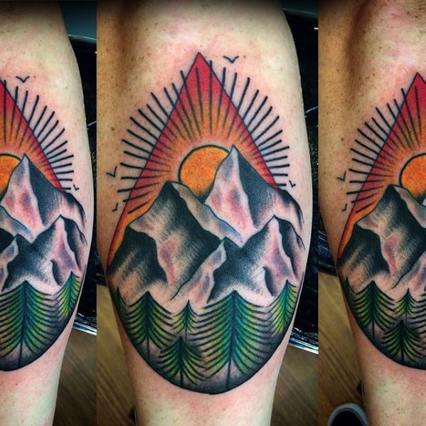 Colorful tattoo with snow-capped mountains, green pine trees, and a bright sunset inside a triangle, radiating with sun rays and birds.