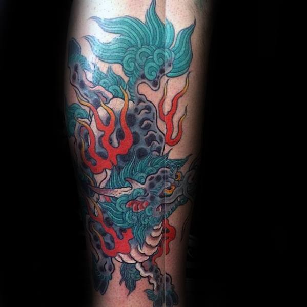 Colorful Kirin tattoo on the calf with teal mane, red flames, and smoky black clouds, depicted in a fierce and dynamic traditional style.