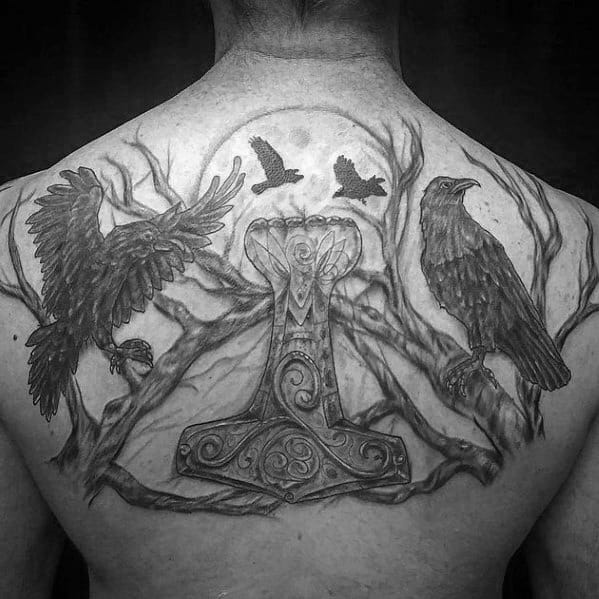 Large back tattoo of Huginn and Muninn with Mjölnir at the center, surrounded by trees, a full moon, and flying ravens in the sky.