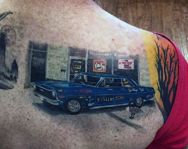 Tattoo of a blue vintage car with signage on its body in front of a storefront