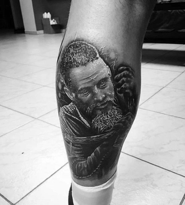 Black and gray tattoo of a bearded man on a person's lower leg