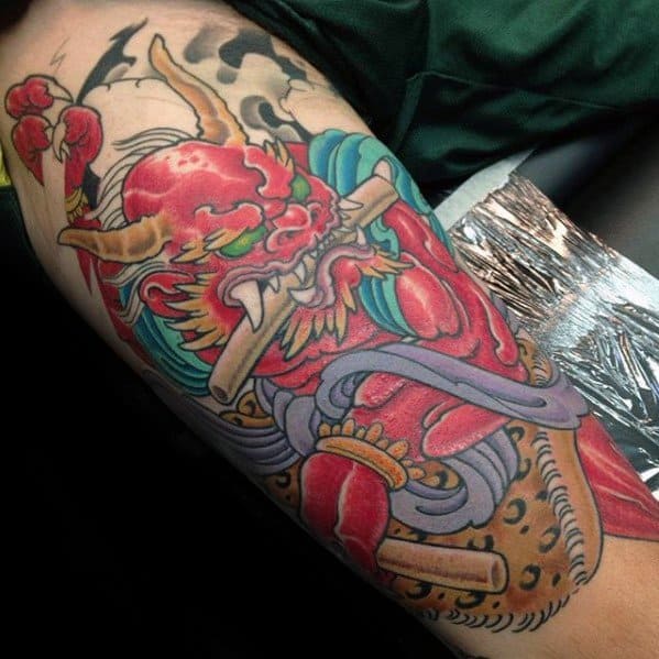 Vibrant Raijin arm tattoo with red thunder god, golden horns, flowing teal hair, and detailed traditional Japanese elements.