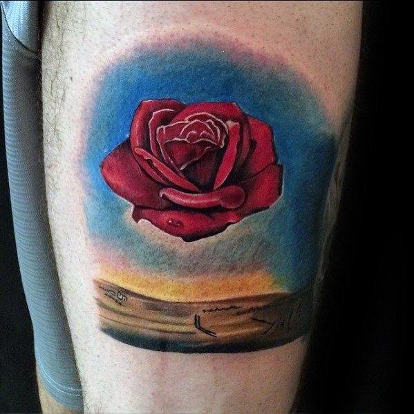 Colorful tattoo of Salvador Dali’s “Meditative Rose,” featuring a floating red rose above a desert landscape with a vivid sky gradient.