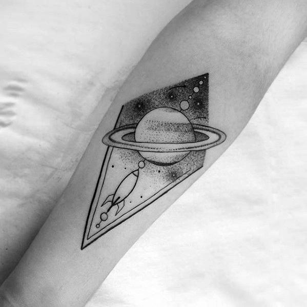 Minimalist Saturn tattoo design for men with dotwork shading, geometric framing, and a small rocket flying through space.